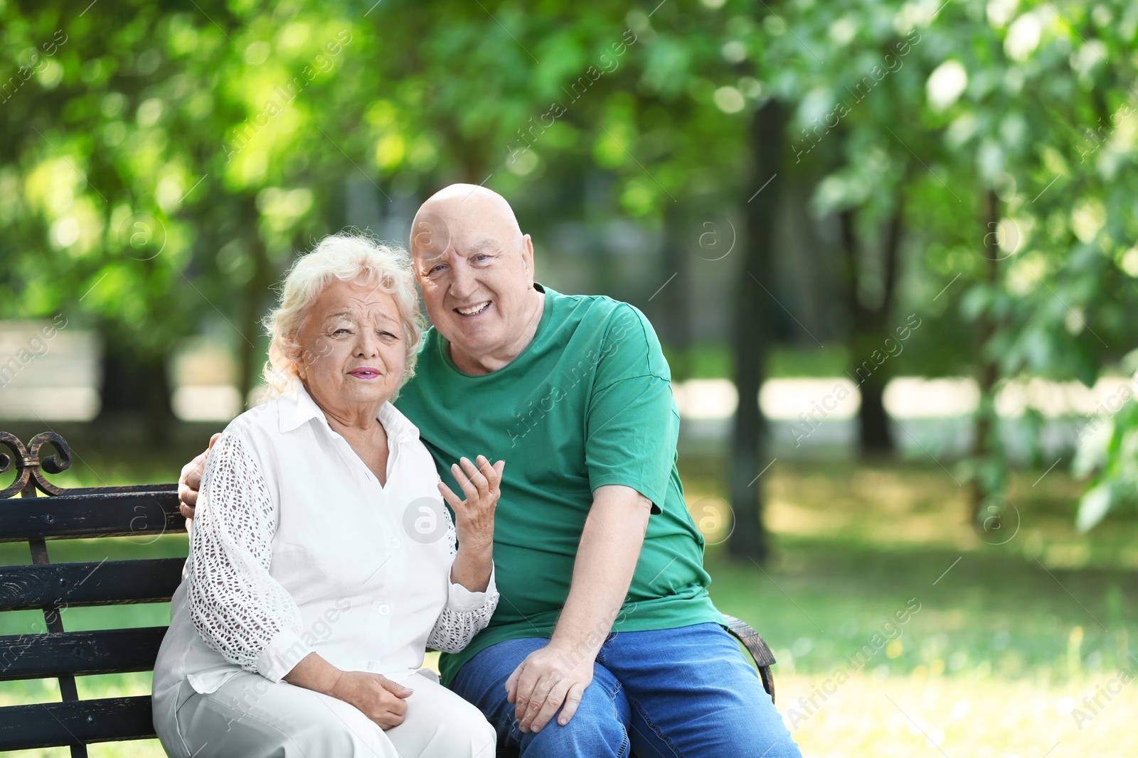 Photo of Elderly couple resting on bench in park