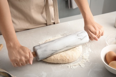 Photo of Woman rolling dough for pastry on table