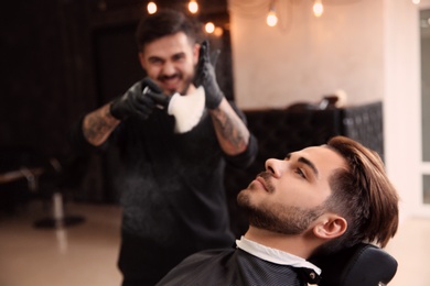 Photo of Young man and hairdresser in barbershop. Professional shaving service