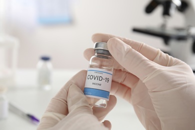Photo of Doctor holding vial with vaccine against Covid-19 indoors, closeup