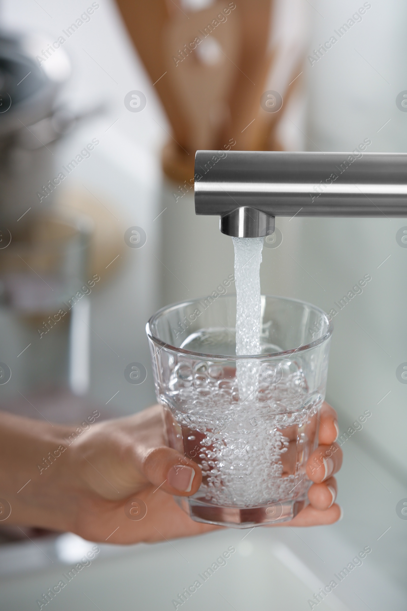 Photo of Woman filling glass with tap water from faucet in kitchen, closeup