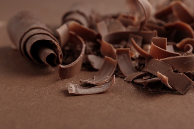 Curls of tasty chocolate on color background, closeup