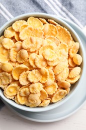 Photo of Bowl of tasty corn flakes on white wooden table, top view