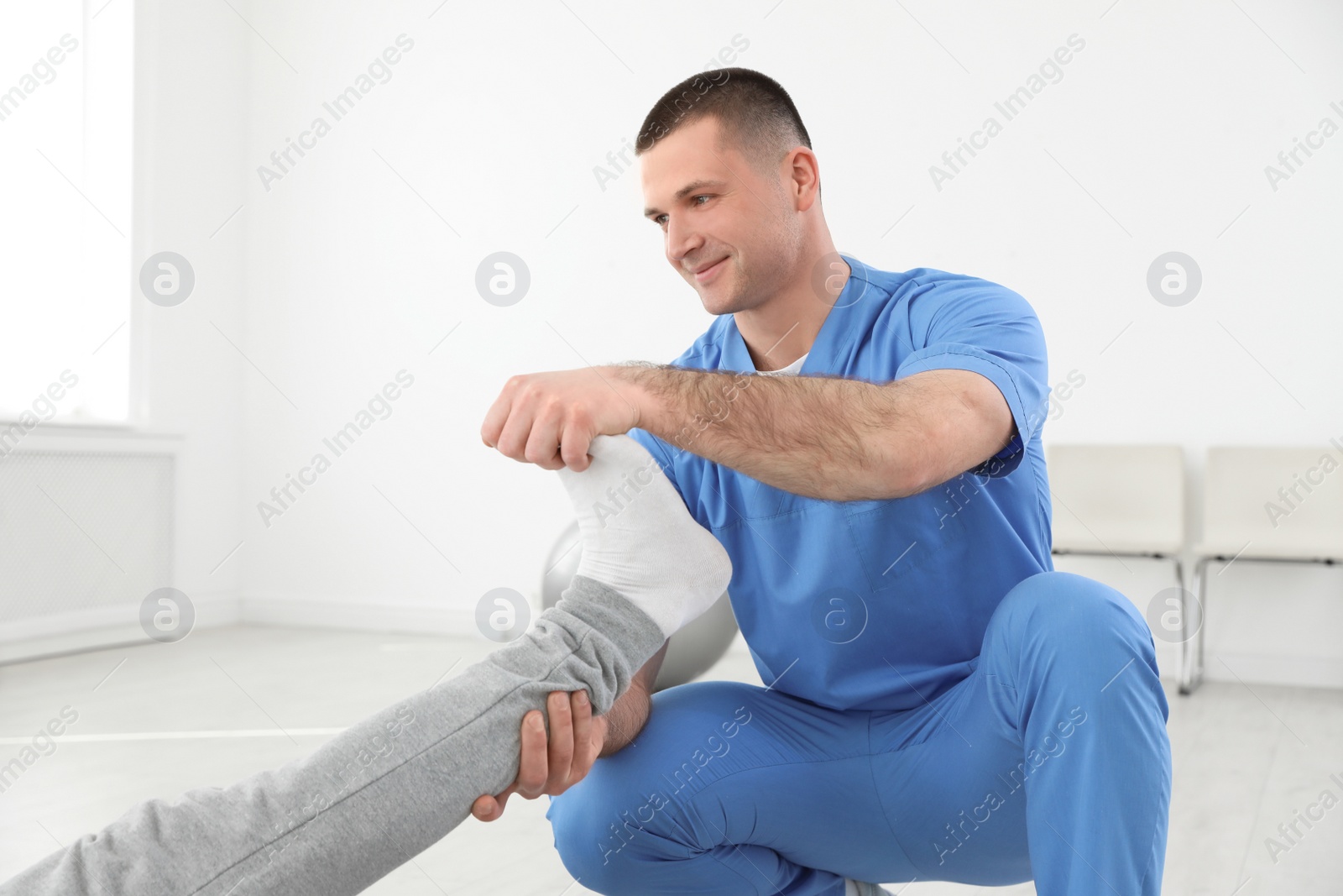 Photo of Professional physiotherapist working with male patient in rehabilitation center