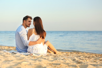 Photo of Happy young couple sitting together on beach