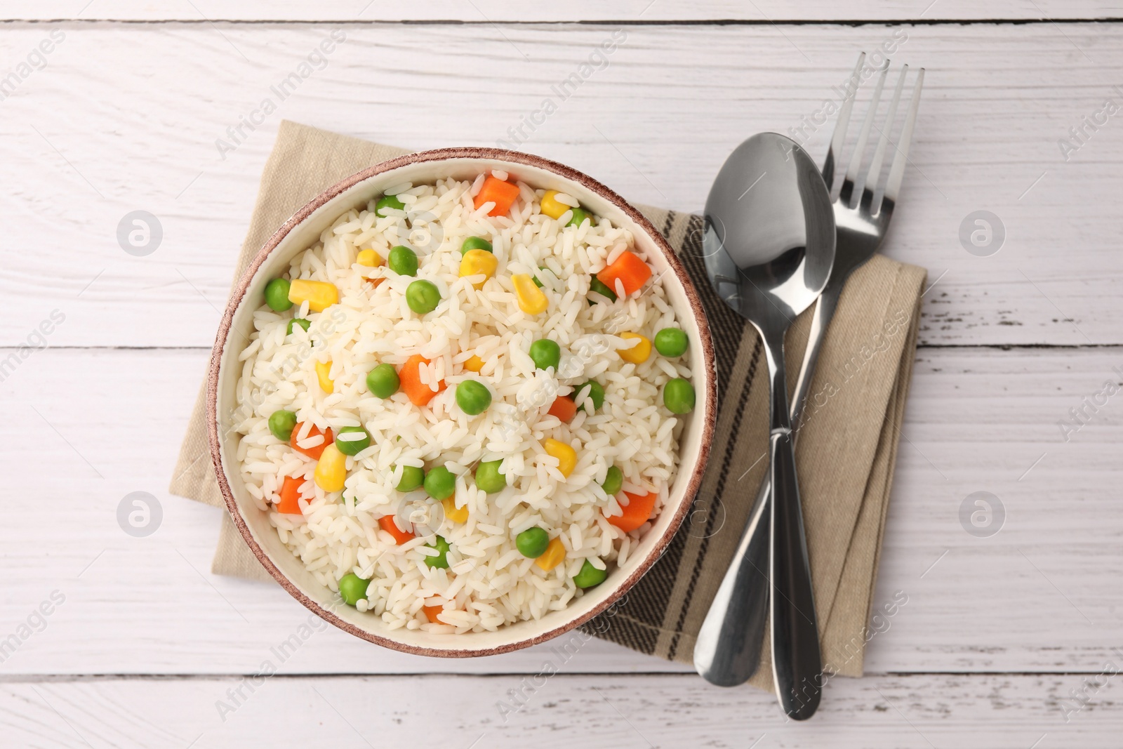 Photo of Bowl of delicious rice with vegetables served on white wooden table, flat lay