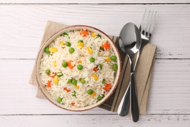 Photo of Bowl of delicious rice with vegetables served on white wooden table, flat lay