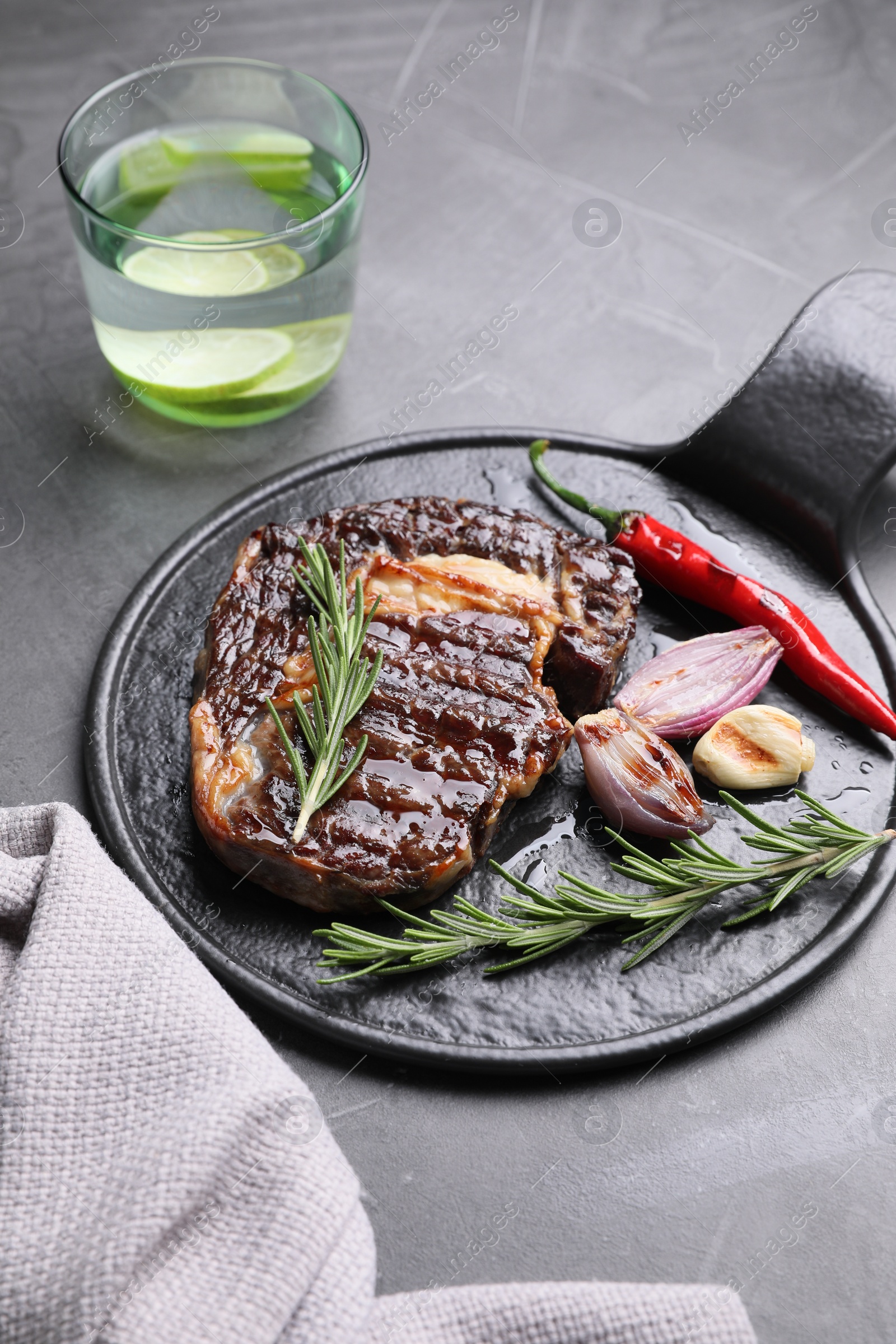 Photo of Delicious grilled beef meat served on gray textured table