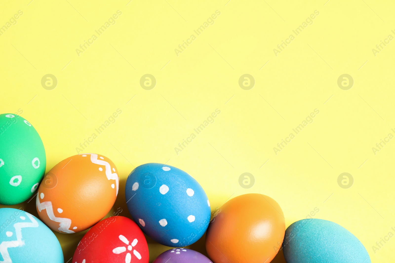 Photo of Colorful Easter eggs on yellow background, flat lay. Space for text