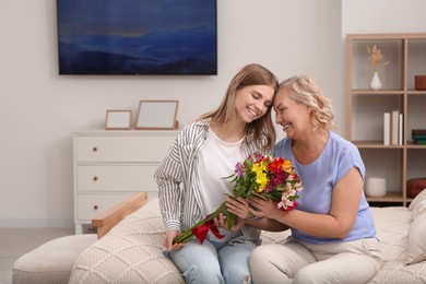 Photo of Young daughter congratulating her mom with flowers at home. Happy Mother's Day