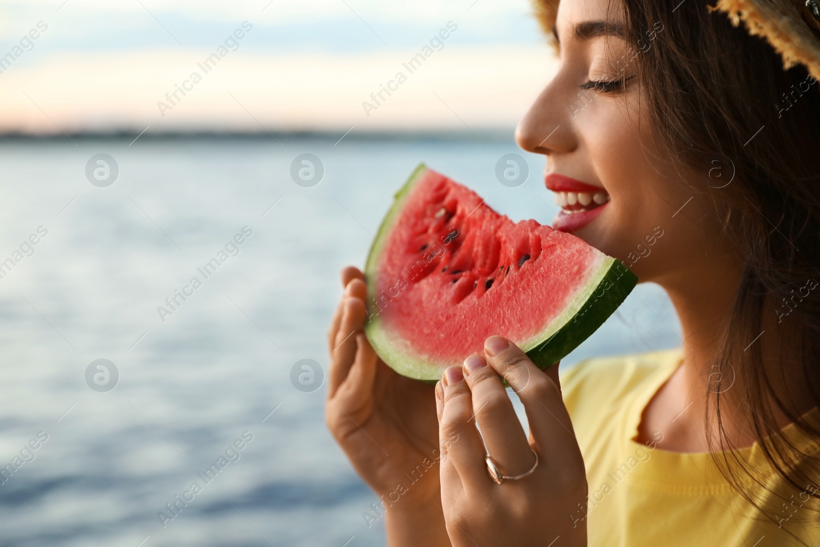 Photo of Beautiful young woman with watermelon near river, closeup