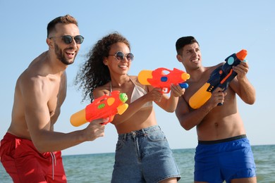 Friends with water guns having fun near sea