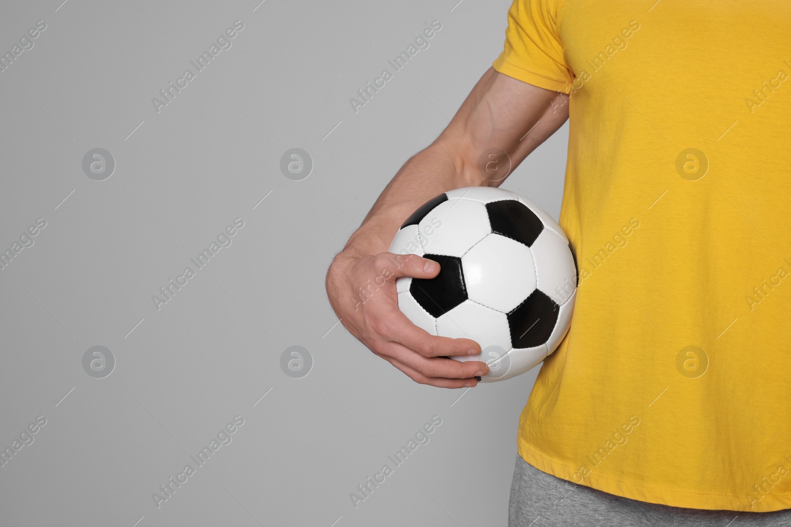 Photo of Athletic man with soccer ball on light grey background, closeup. Space for text