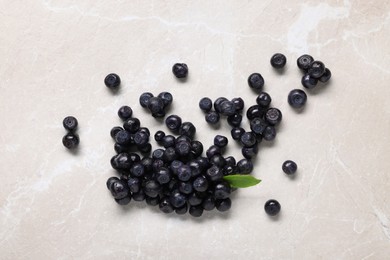 Photo of Ripe bilberries and leaf on light marble table, flat lay