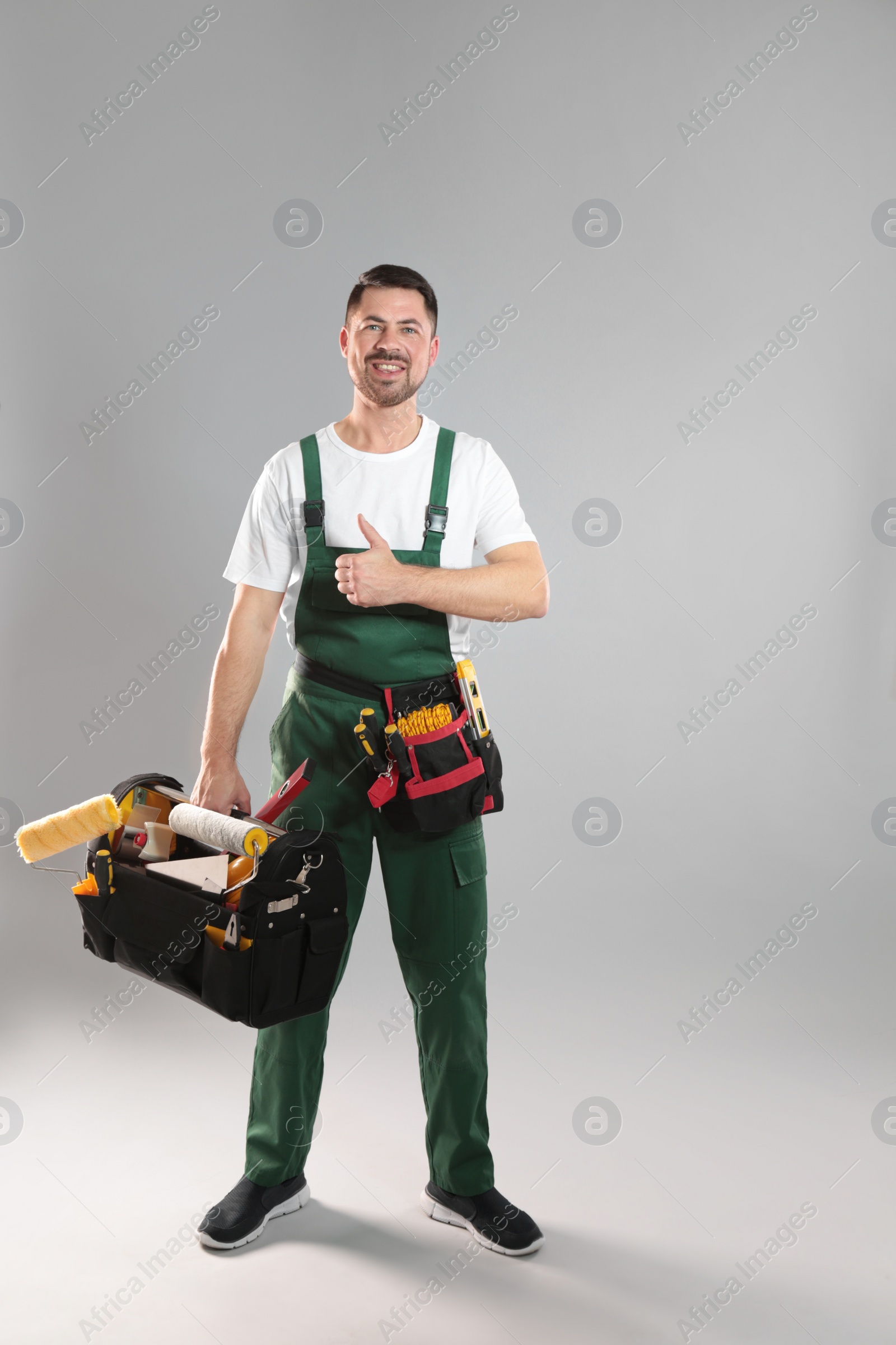 Photo of Full length portrait of professional construction worker with tools on grey background