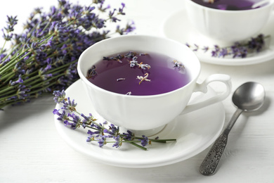 Photo of Fresh delicious tea with lavender and beautiful flowers on white wooden table