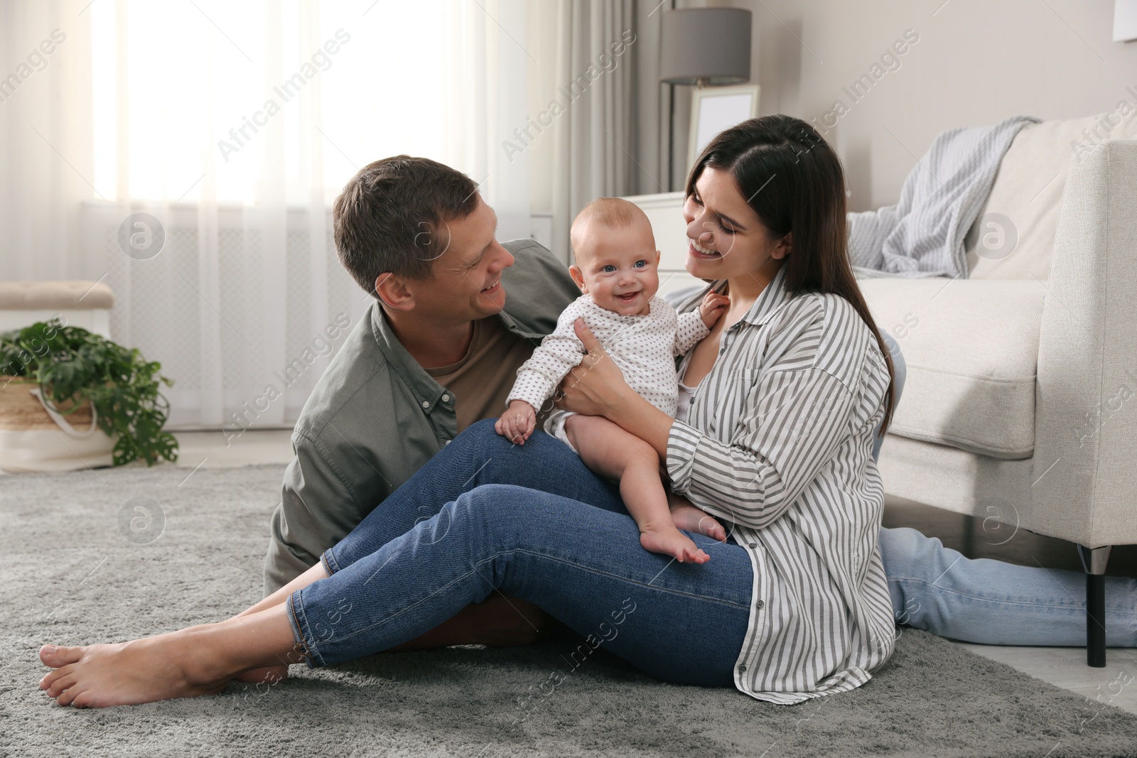 Photo of Happy family with their cute baby on floor in living room