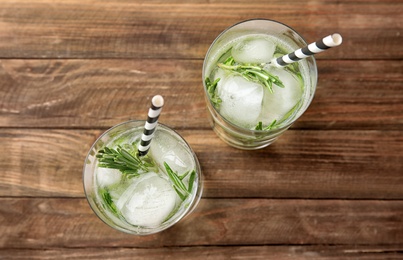 Photo of Glasses of refreshing cucumber cocktail with rosemary on wooden table, top view