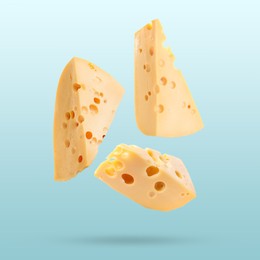 Image of Pieces of tasty cheese falling on light blue background