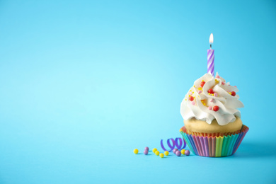 Photo of Delicious birthday cupcake with candle on light blue background. Space for text