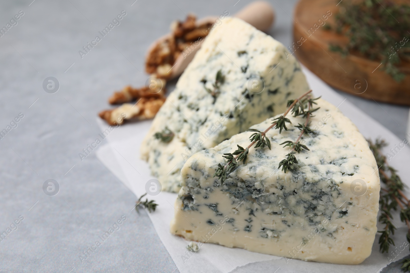 Photo of Tasty blue cheese with thyme on grey table, closeup. Space for text