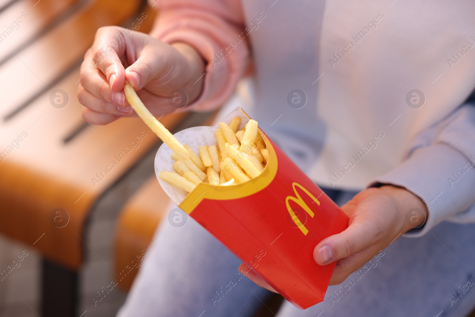 Photo of Lviv, Ukraine - September 26, 2023: Woman eating McDonald's french fries outdoors, closeup