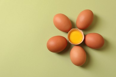 Photo of Flower made with cracked and whole chicken eggs on olive background, flat lay. Space for text