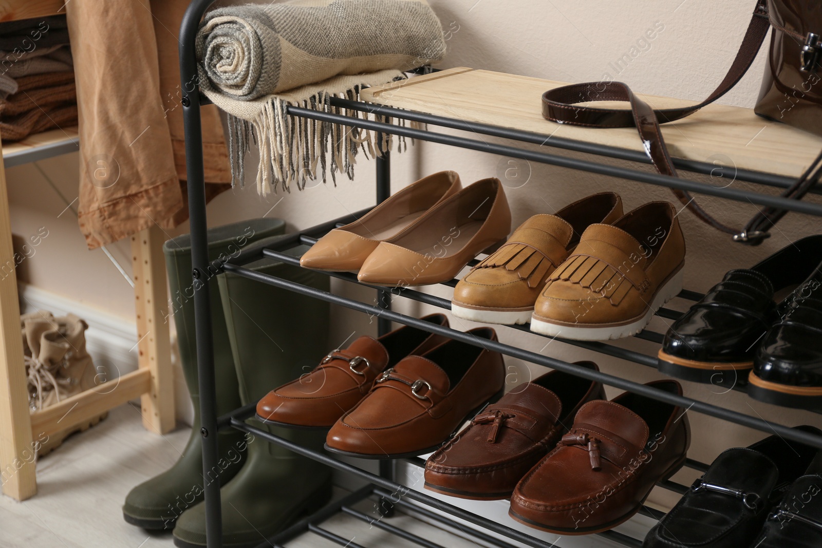 Photo of Rack with different shoes near beige wall