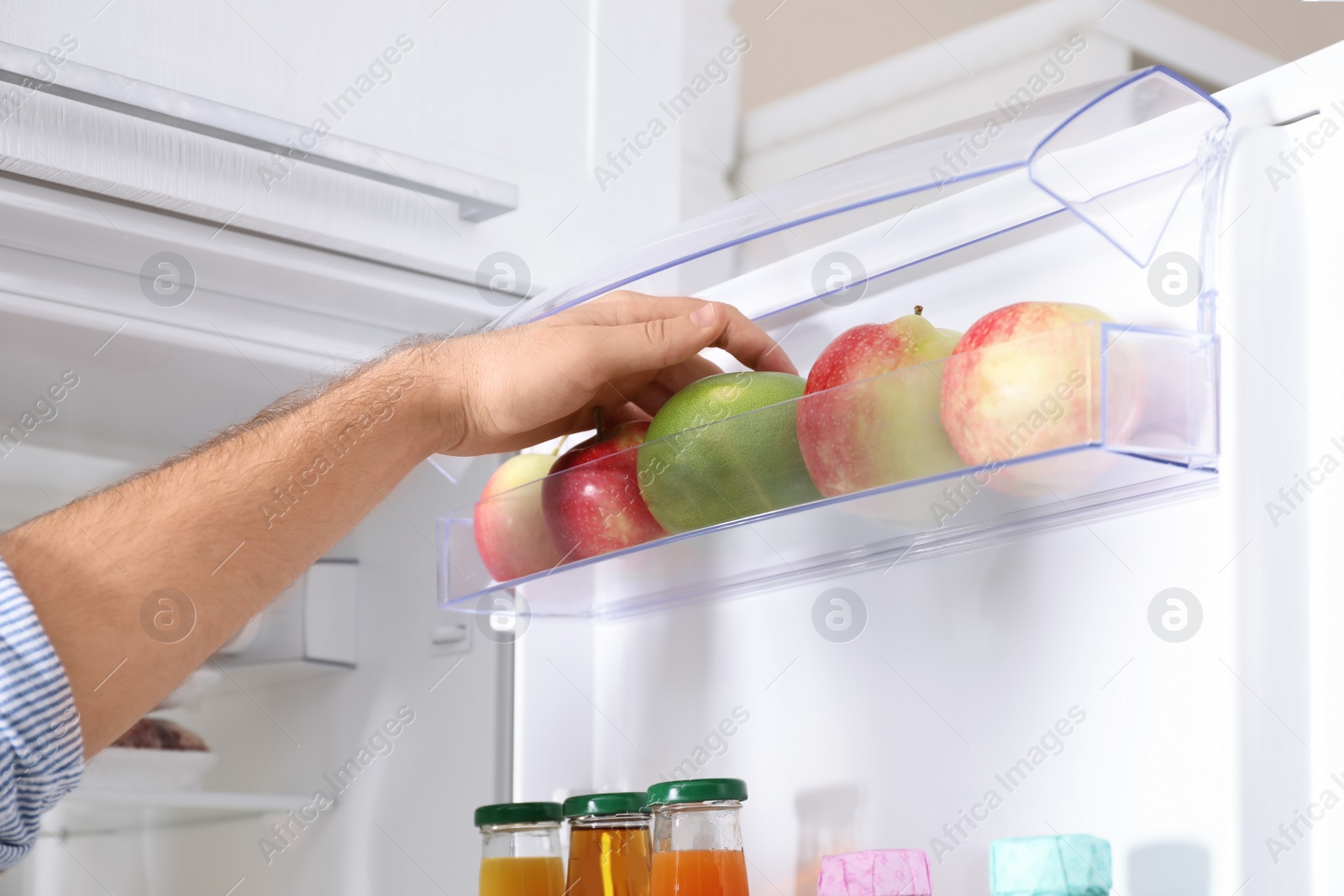 Photo of Man taking fruit out of refrigerator in kitchen, closeup