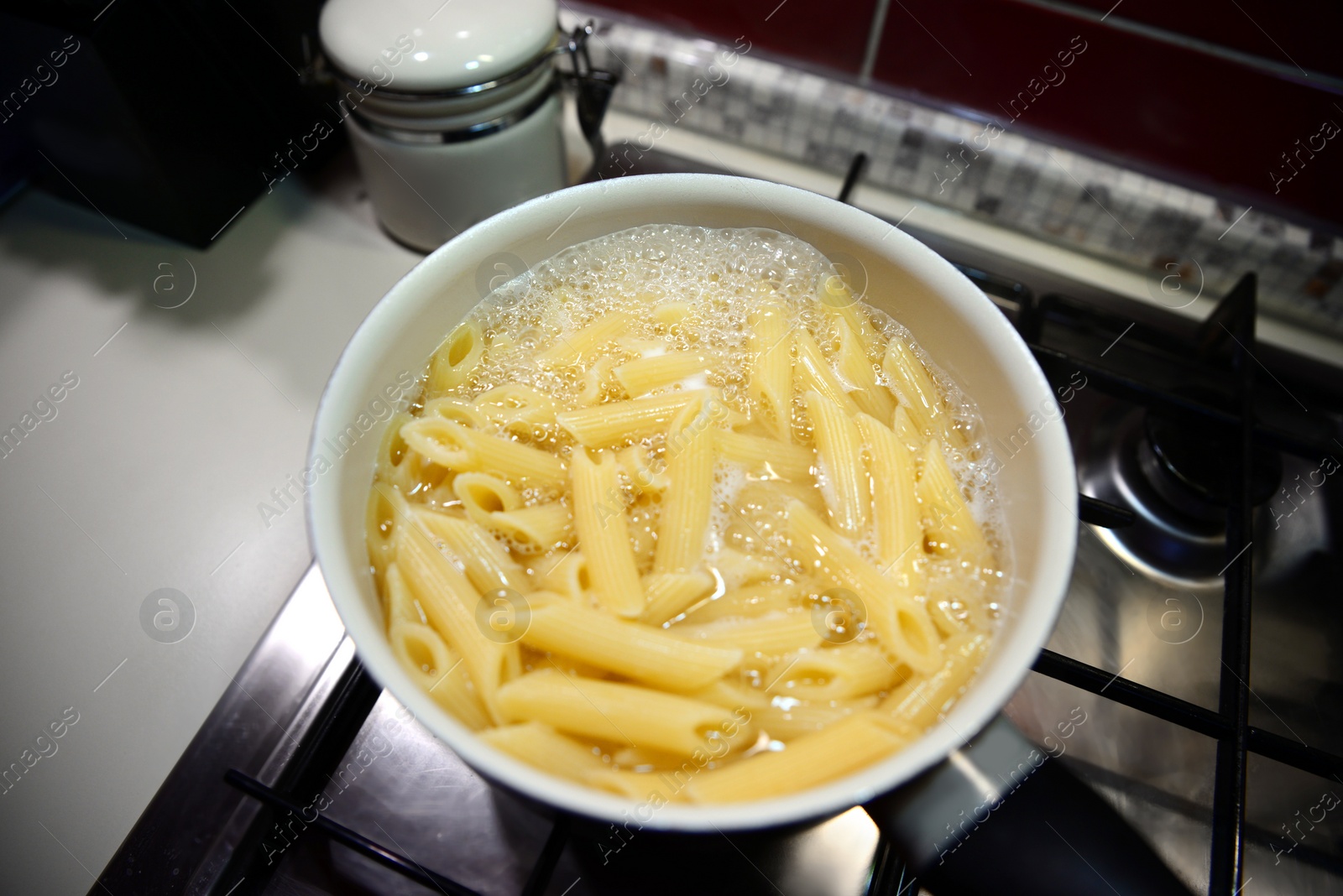 Photo of Cooking tasty pasta in pot on stove indoors, above view