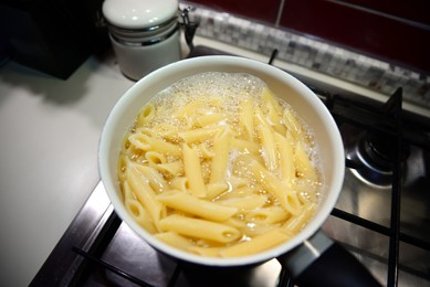 Photo of Cooking tasty pasta in pot on stove indoors, above view