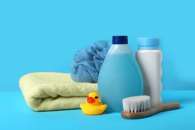 Photo of Baby cosmetic products, bath duck, accessories and towel on light blue background