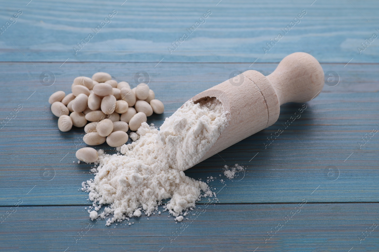 Photo of Kidney bean flour and seeds on light blue wooden table