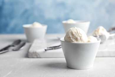 Photo of Bowl with tasty vanilla ice cream on table