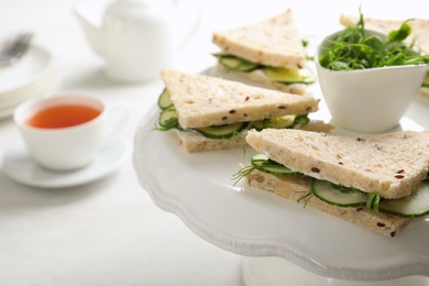 Photo of Stand with tasty cucumber sandwiches on table, closeup. Space for text