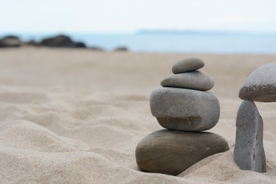 Photo of Stacks of stones on beautiful sandy beach near sea, space for text