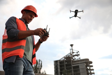 Builder operating drone with remote control at construction site. Aerial survey