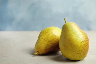 Photo of Ripe juicy pears on grey stone table against blue background. Space for text