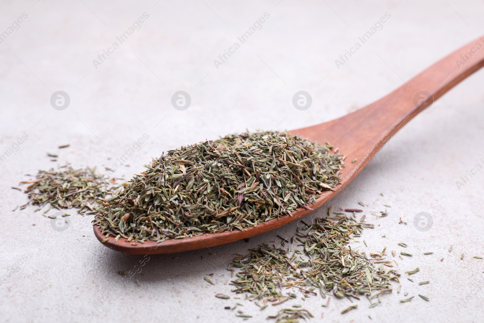 Photo of Spoon with dried thyme on grey table, closeup