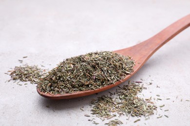 Spoon with dried thyme on grey table, closeup