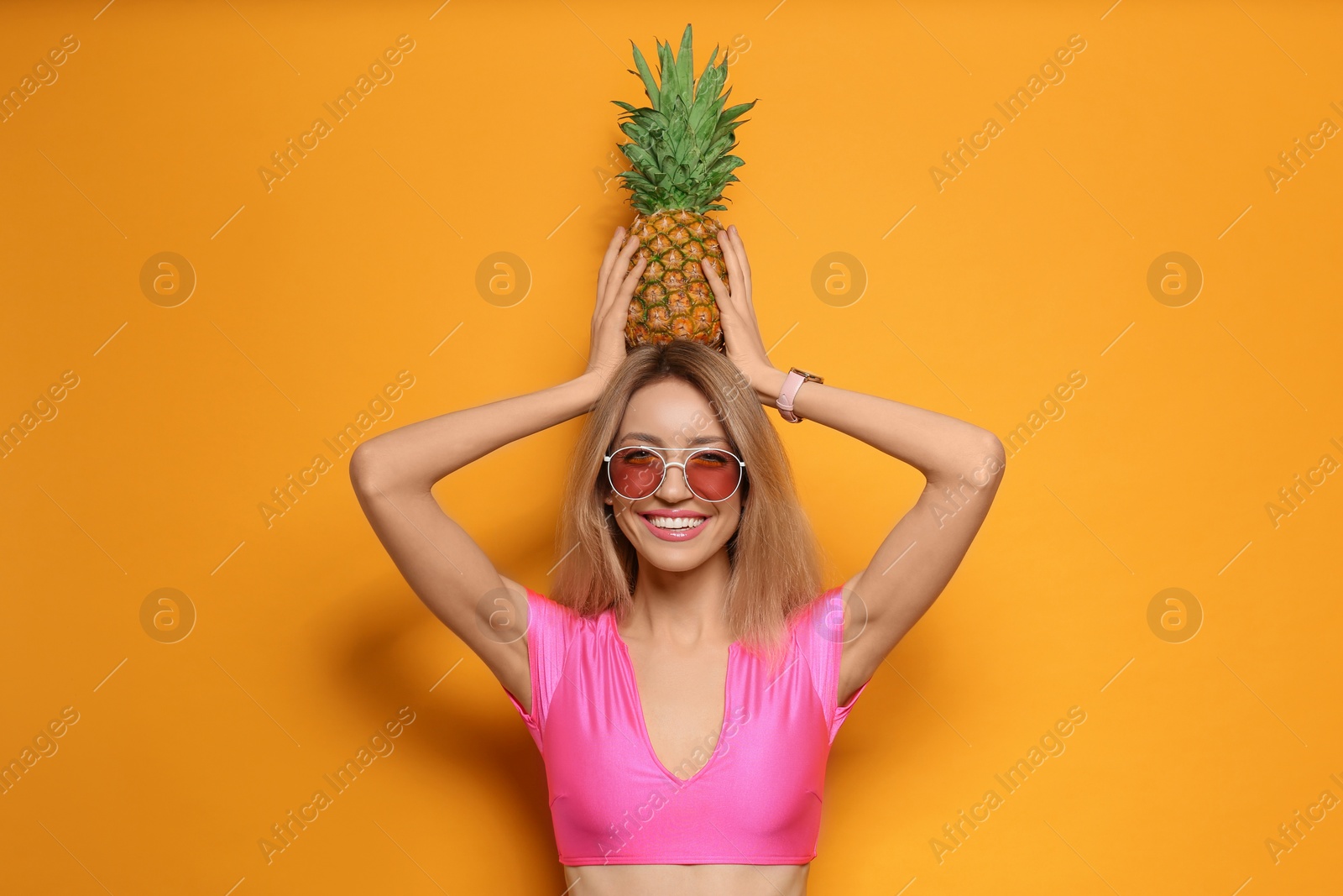 Photo of Young woman with fresh pineapple on yellow background. Exotic fruit