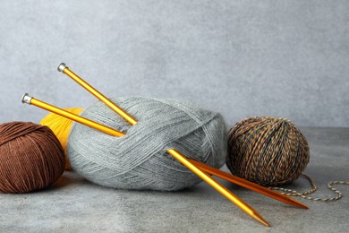 Photo of Soft woolen yarns and knitting needles on grey table