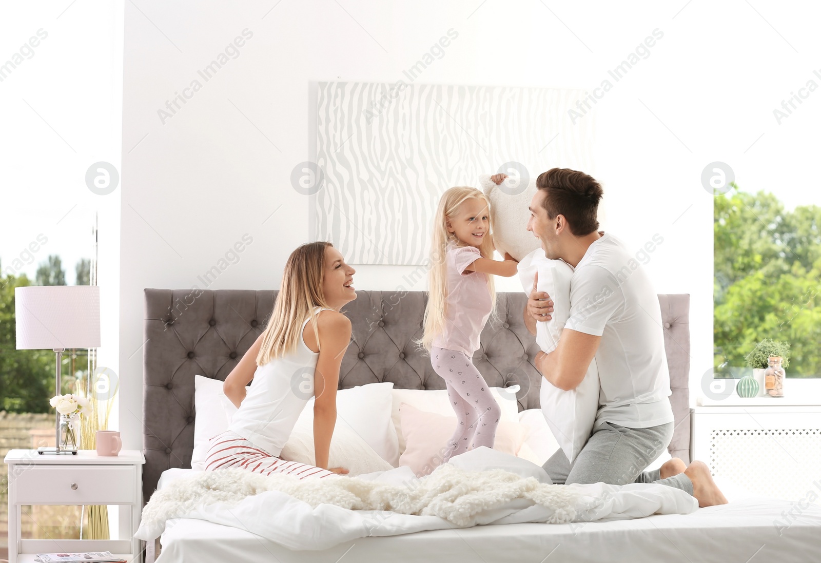 Photo of Happy family having pillow fight on bed at home