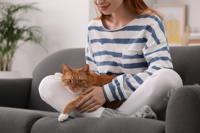 Photo of Woman with her cute cat on sofa at home, closeup