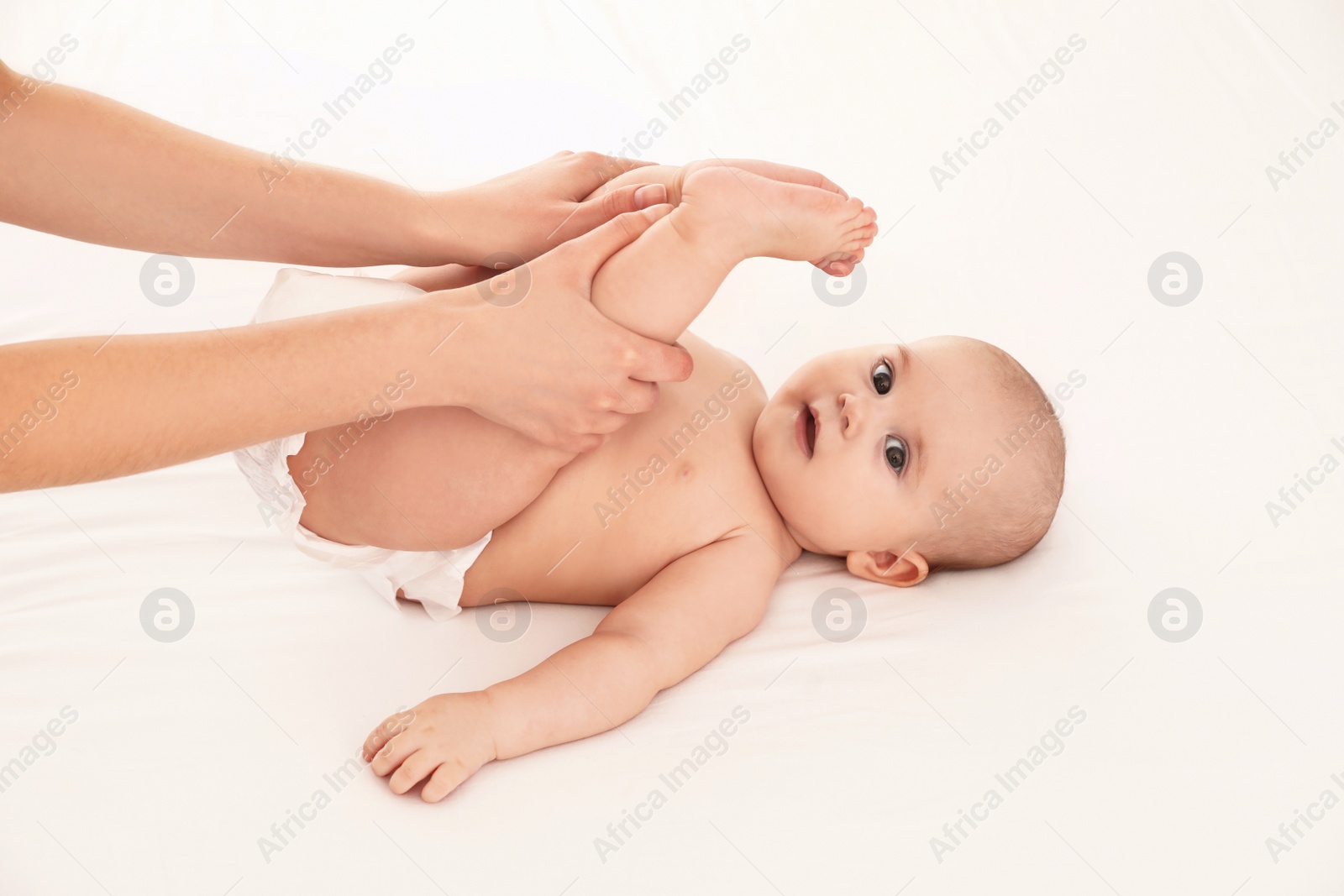 Photo of Mother and her cute child on white bed. Baby massage and exercises