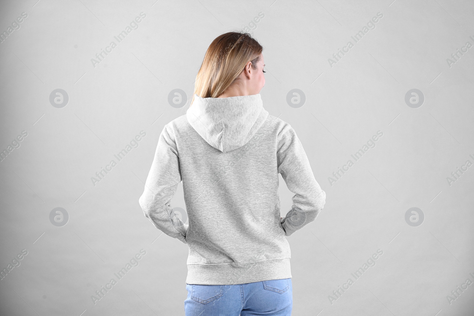 Photo of Woman in hoodie sweater on light background. Space for design