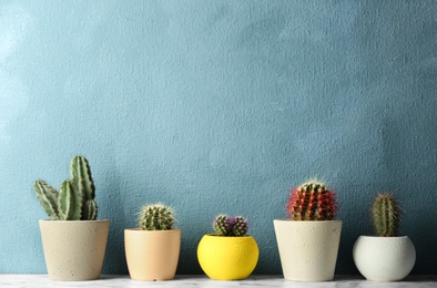 Photo of Different potted cacti on table near color background, space for text. Interior decor