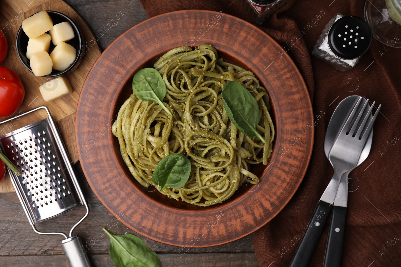 Photo of Tasty pasta with spinach served on wooden table, flat lay