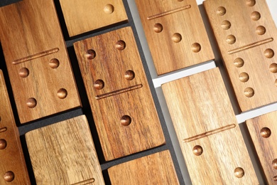 Photo of Set of wooden domino tiles on color background, flat lay
