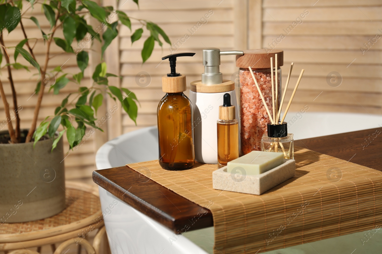 Photo of Wooden tray with spa products on bath tub in bathroom